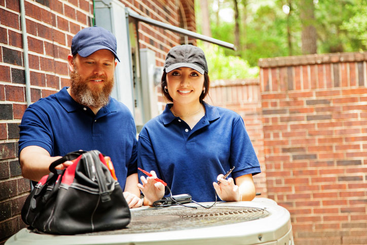 Two technicians diagnosing A/C unit