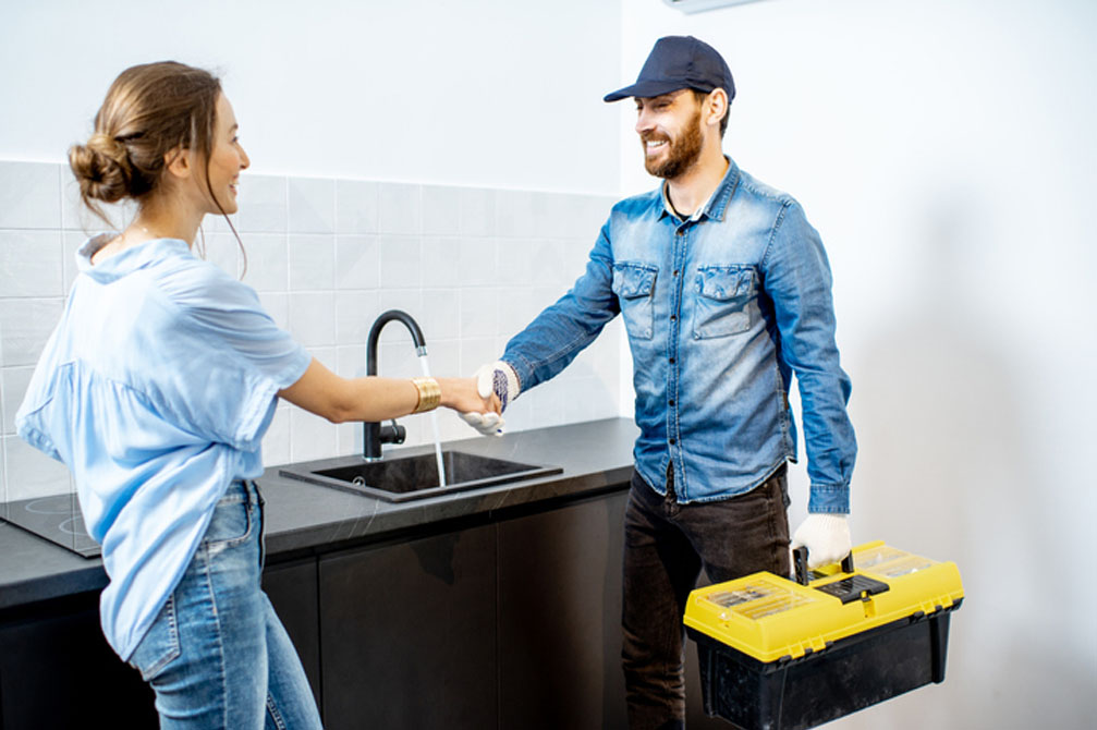 Technician shaking hands with customer in kitchen